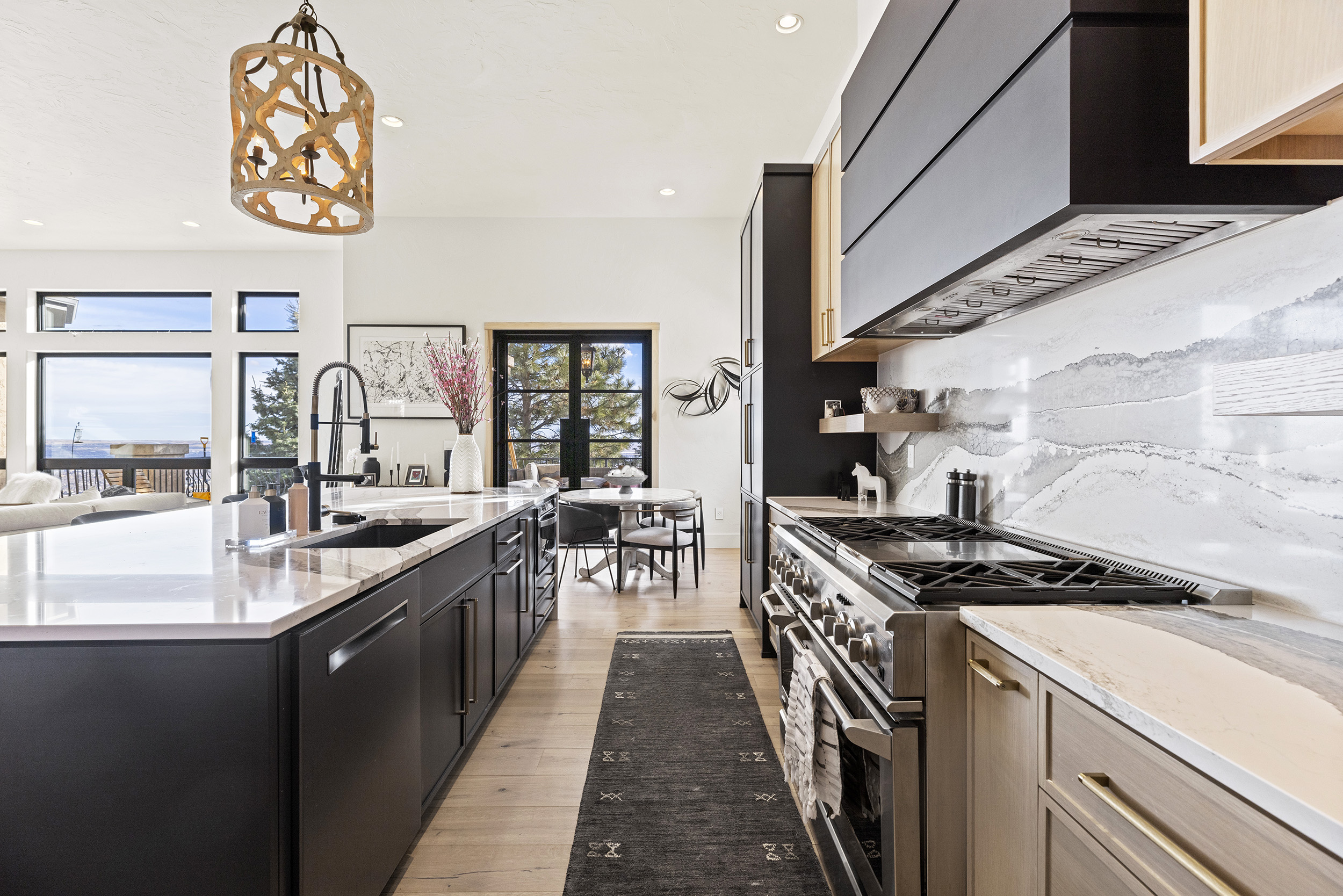 Large granite island countertop with sink. Large custom gas range with double oven. Custom ventilation hood. Colorado Spring kitchen remodeling by Alpine Contracting. 