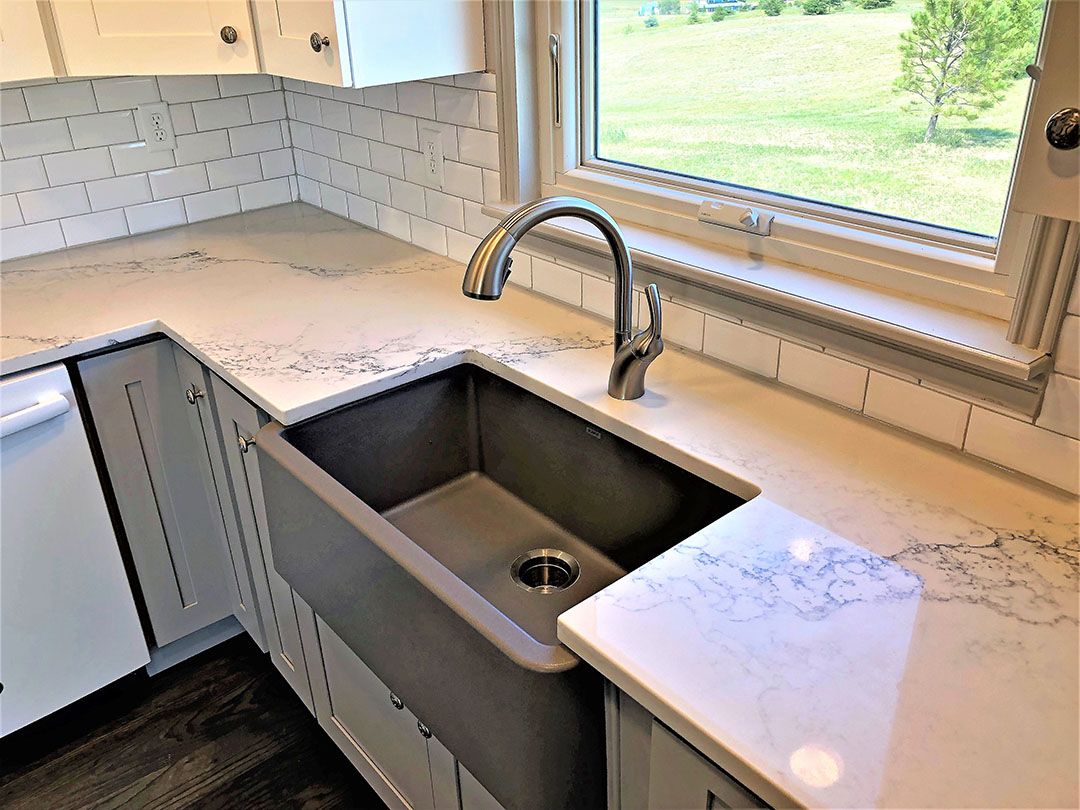 Large farmhouse style sink with window overlooking backyard. Granite countertops. Kitchen renovation.
