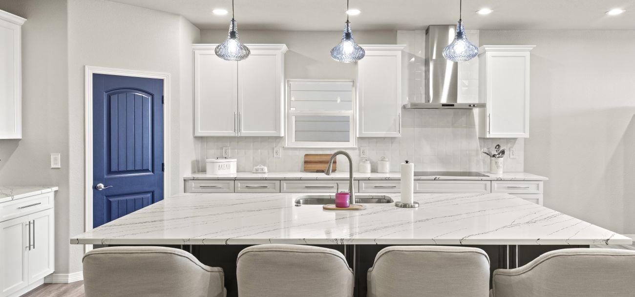 Kitchen remodel. Large quartz island countertop with sink. White cabinets. Blue pantry door. Located in Colorado Springs.