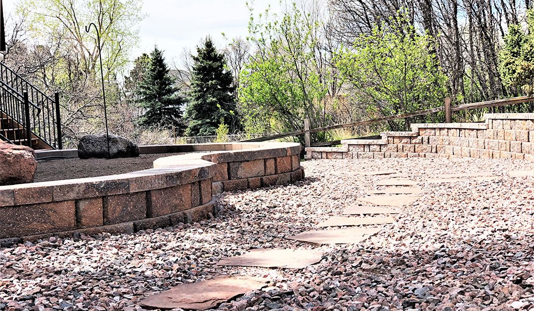 Raised flowerbed retaining walls with crushed and stone paver walkway.