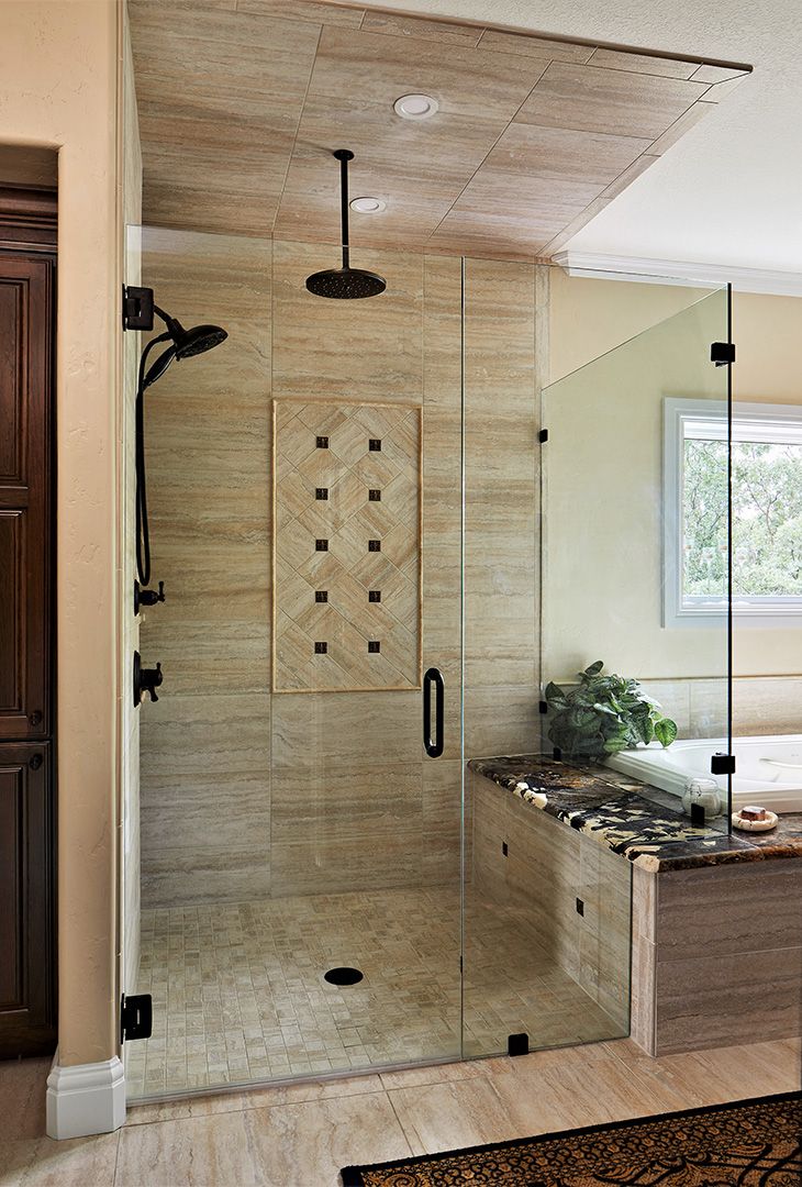 Glass shower enclosure with custom tile, overhead rain shower head, body spray.