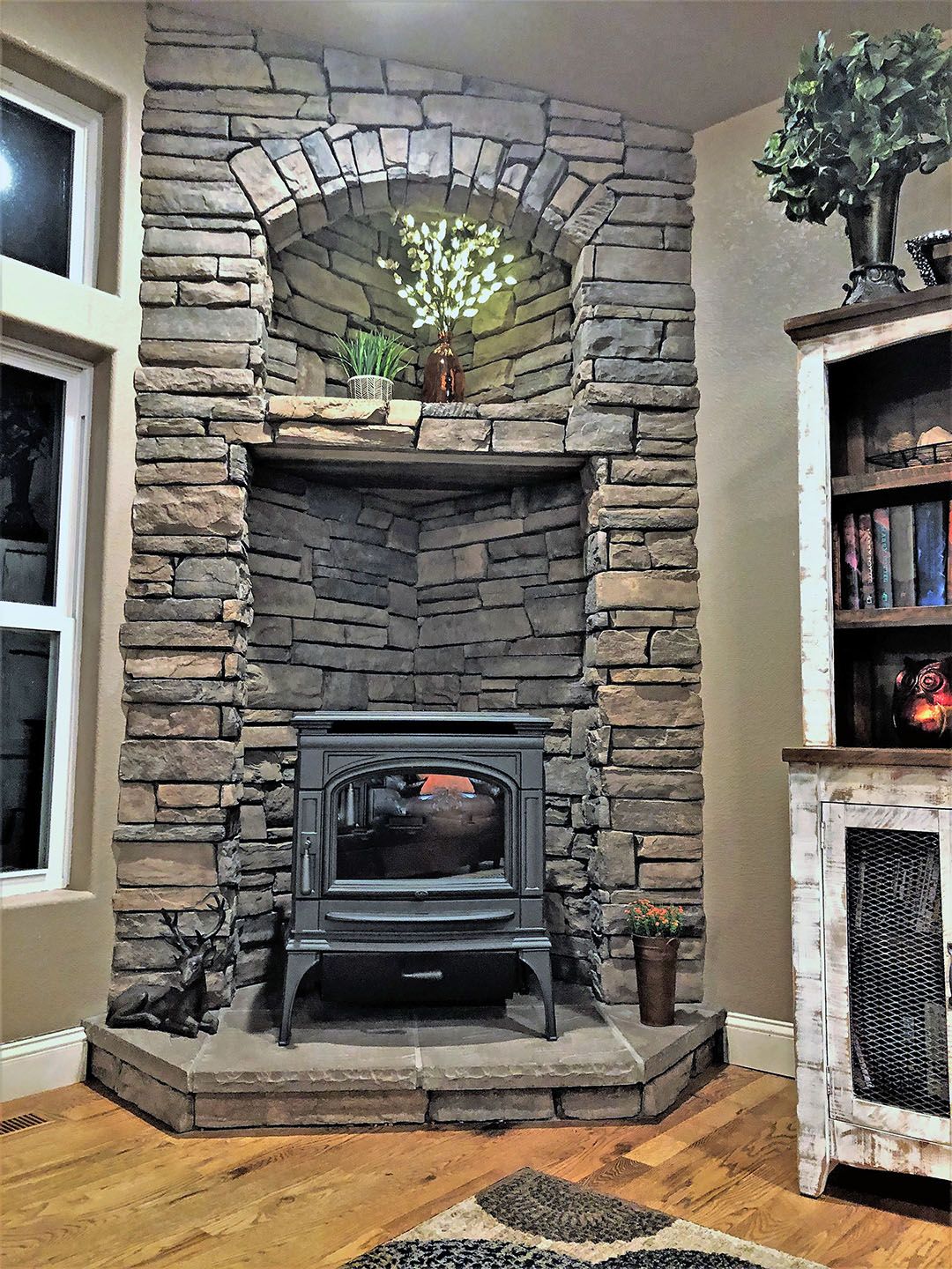 A corner pellet stove with stone enclosure.