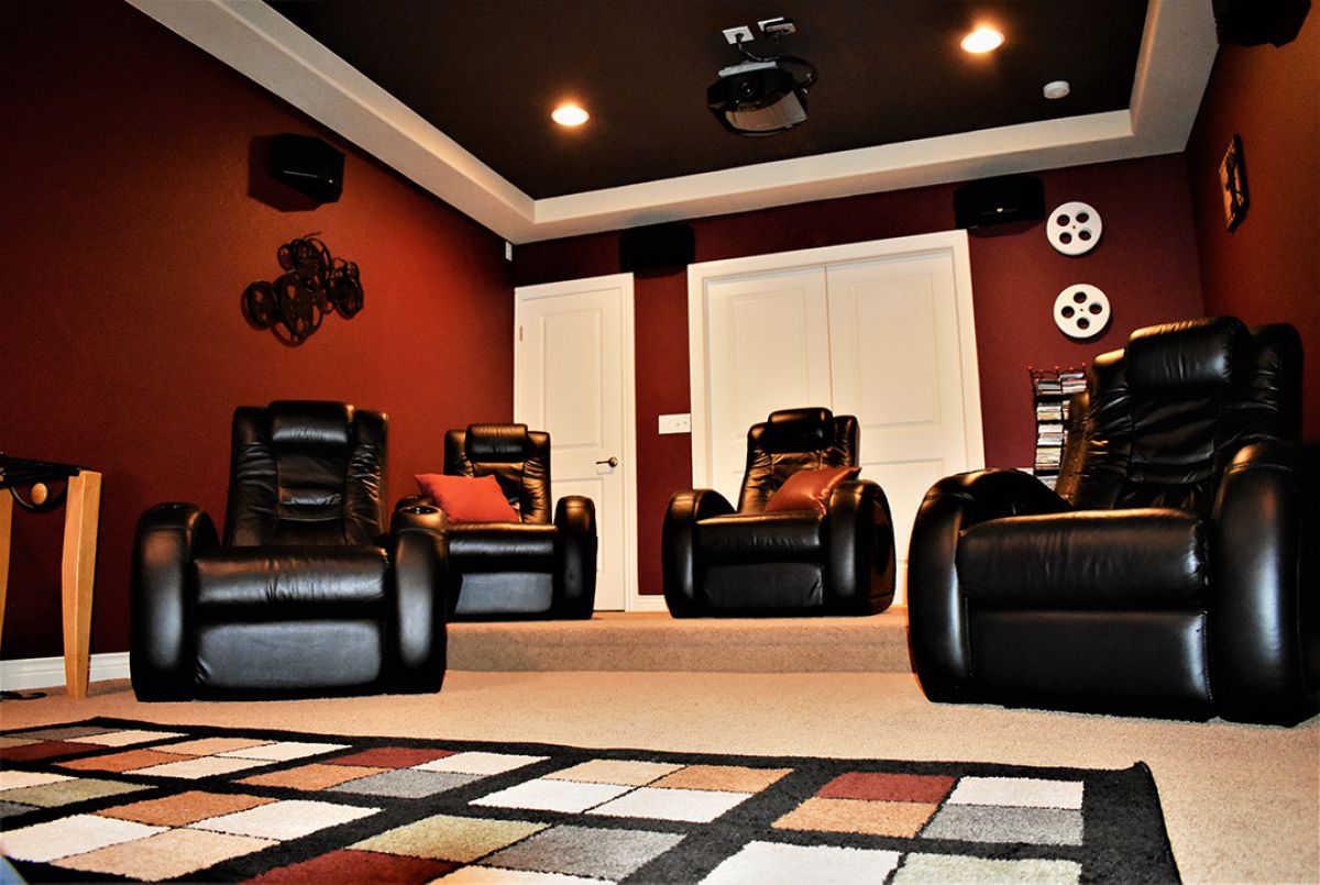 Home theater tiered seating with leather reclining chairs, projector, and recessed lighting.