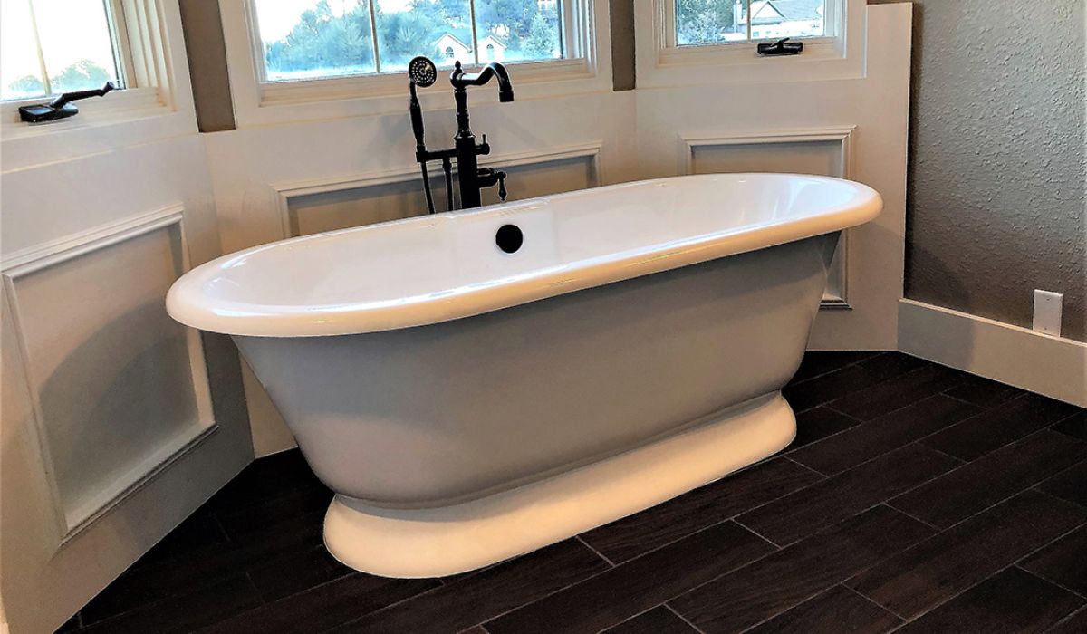 Luxury stand-alone white bath tub with black faucets.