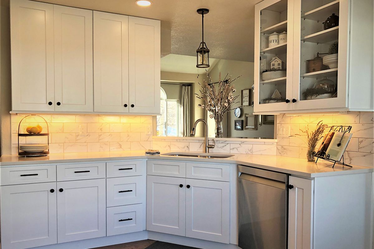 Kitchen remodel with white cabinets, stainless steel appliances, and sink with open pass-through to the living room.
