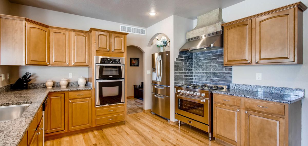Kitchen makeover with oak cabinets, granite countertops, stove with hood.