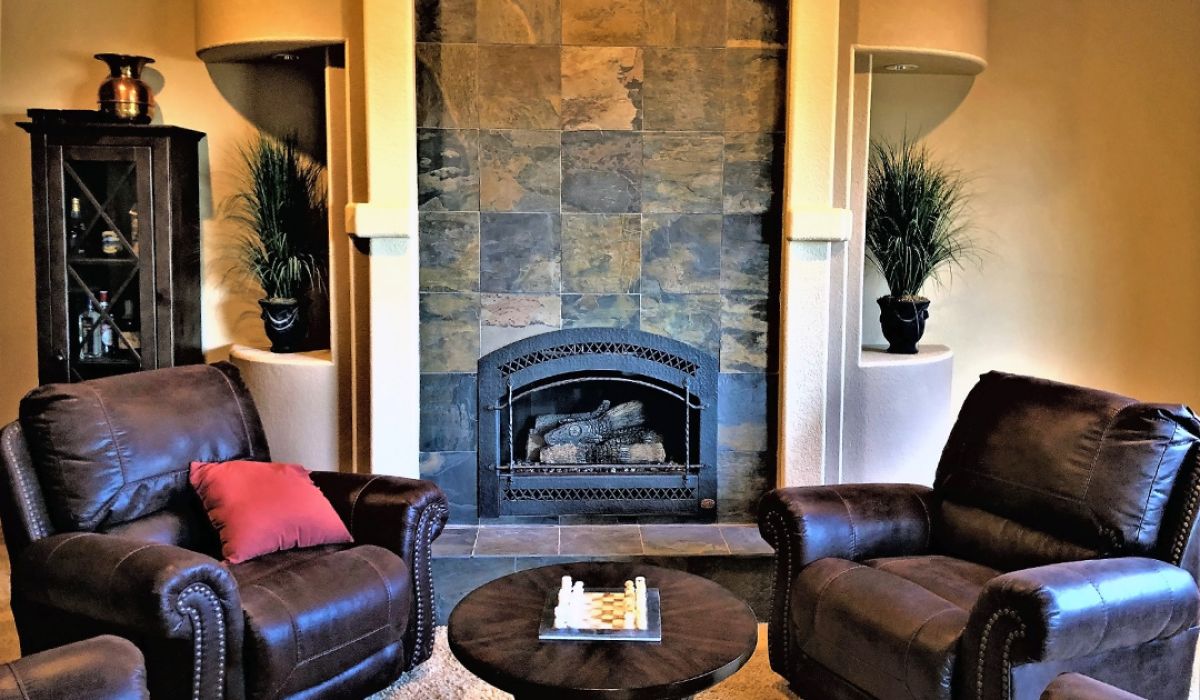 A stone tile fireplace withe two leather chairs.