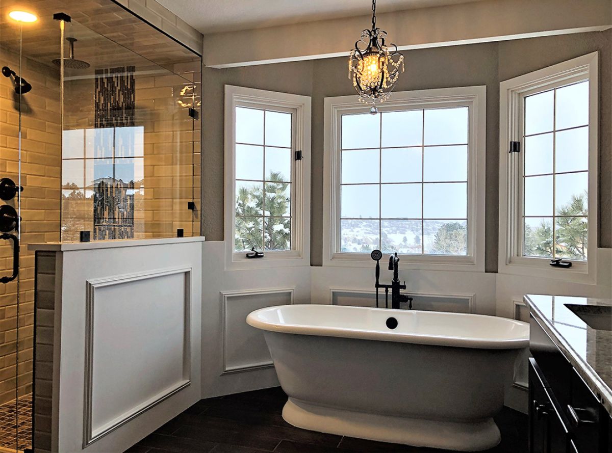 Custom bathroom renovation in Colorado Springs. Artisan tub, white trim, glass shower enclosure, bay window, snowing outside.