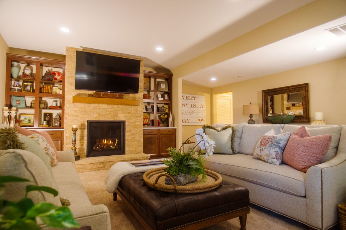 Finished basement with stone fireplace and a TV mounted above it.